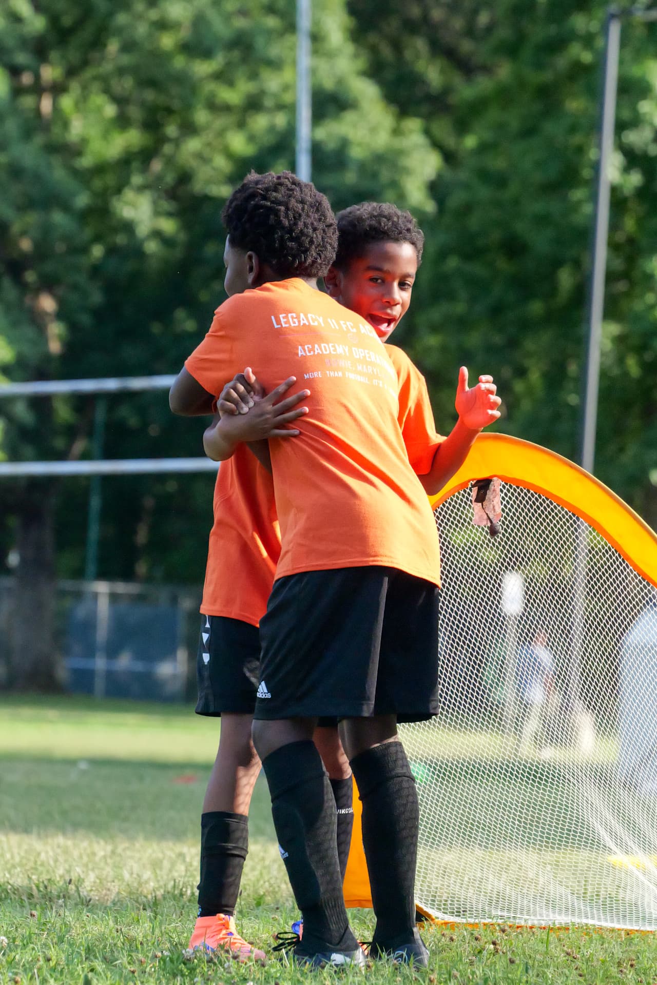 Two young Legacy players celebrating a goal beside the net